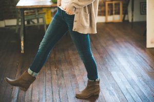 Woman in jeans and boots walking on hardwood floor